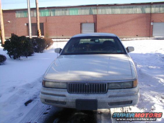 White Mercury Grand Marquis parked in snow, front view