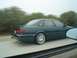 2002 Ford Taurus - This dark green sedan, likely a 1998 model, is captured in motion on a highway, its side profile and custom wheels.