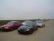 2002 Ford Taurus - A group of sedans, including red and black Ford Tauruses, are parked on the side of a road.