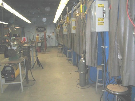 Workshop with multiple welding stations, welding equipment, and gas cylinders