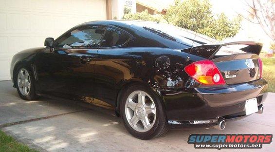 Black 2003 Hyundai Tiburon coupe with a rear spoiler, parked in a driveway