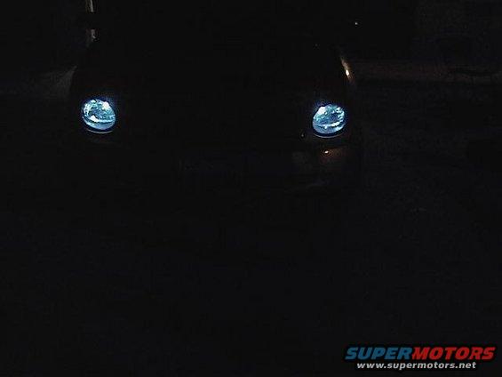 Dark car front with illuminated headlights