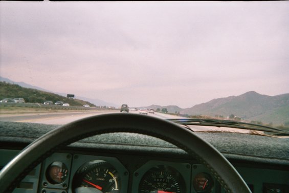 View from inside a car, showing dashboard gauges and a highway with traffic