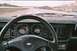 1985 Ford Mustang - Interior view of a car driving on a highway, showing the dashboard gauges and steering wheel.