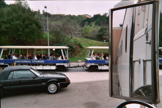 Black convertible parked next to Universal Studios tram tour vehicles