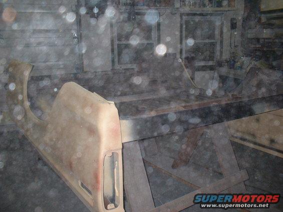 Faded beige truck fender and bed panel on sawhorses in a garage