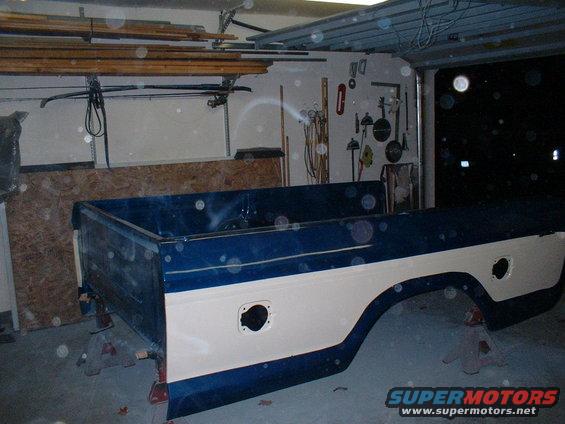 Pickup truck bed on jack stands in a garage. It's blue and cream colored