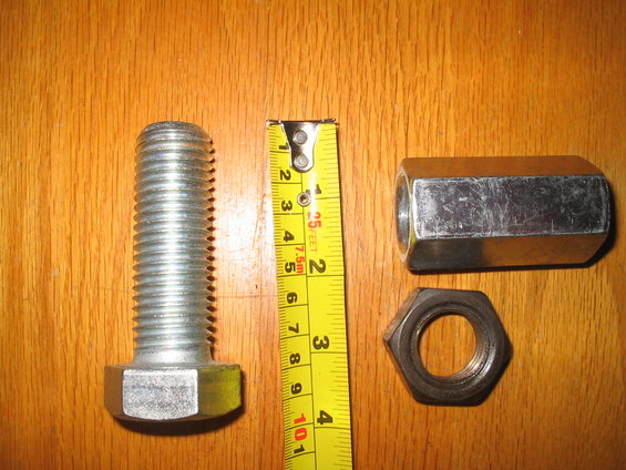 Bolt, coupling nut, and hex nut with a yellow measuring tape on a wooden surface