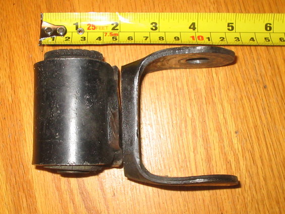 Black metal suspension part next to a yellow tape measure showing inches and centimeters