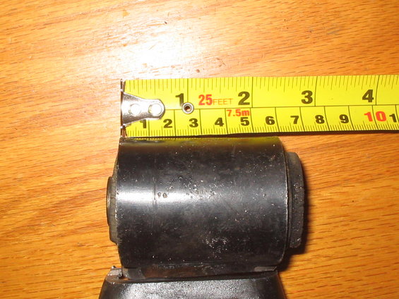 Measuring a black suspension bushing with a yellow tape measure. The bushing is about 2.5 inches wide