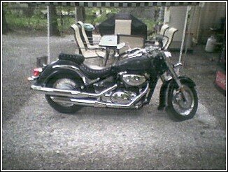 Black cruiser motorcycle parked on gravel, side view