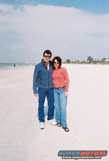 Couple standing on a sandy beach with the ocean and sky in the background