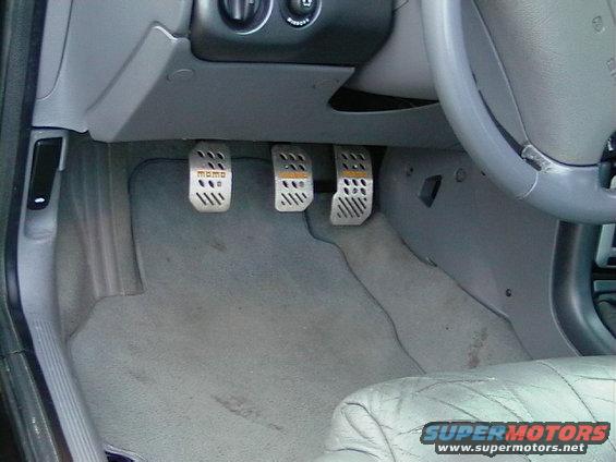 Car interior showing three aftermarket pedals, one labeled 'Momo'