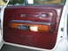 1988 Mercury Grand Marquis - Close-up of a car's interior door panel, maroon upholstery and wood grain accents.