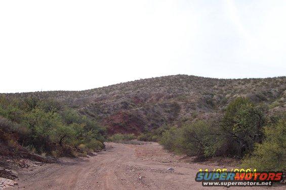 Dirt road winding through desert hills under a bright sky