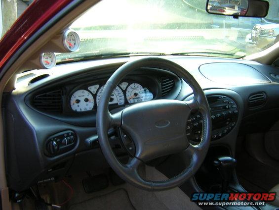 1997 Ford Taurus interior with aftermarket gauges above the dashboard and a dark gray steering wheel