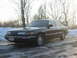 1992 Ford Crown Victoria - A dark sedan is parked on a road with snow and ice on the ground, with trees in the background.