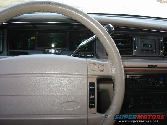 Tan dashboard and steering wheel of a 1992 Ford Crown Victoria with digital gauges and an aftermarket stereo