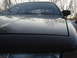 1992 Ford Crown Victoria - Front view of a dark-colored car, focusing on the hood and windshield with reflections of bare trees.