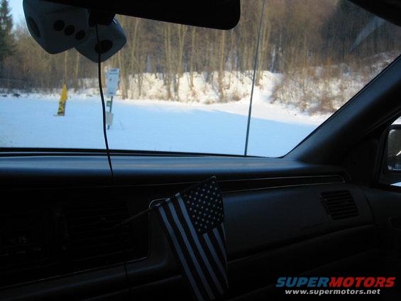 1992 Ford Crown Victoria interior dashboard with an American flag and fuzzy dice hanging from the rearview mirror