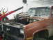 1981 Chevrolet C/K Pickup - A truck's engine is being removed using an engine hoist in a garage setting.