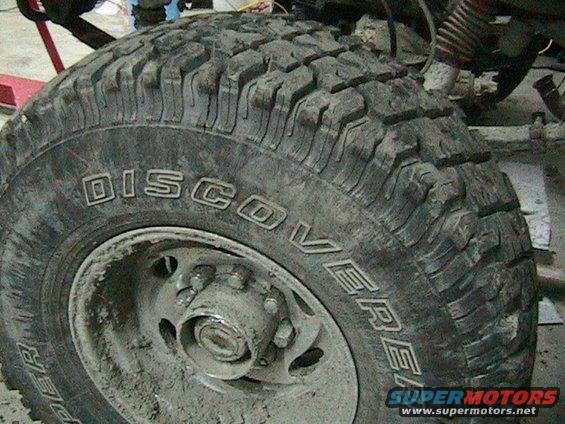 Close-up of a muddy tire with 'DISCOVERER' written on the sidewall