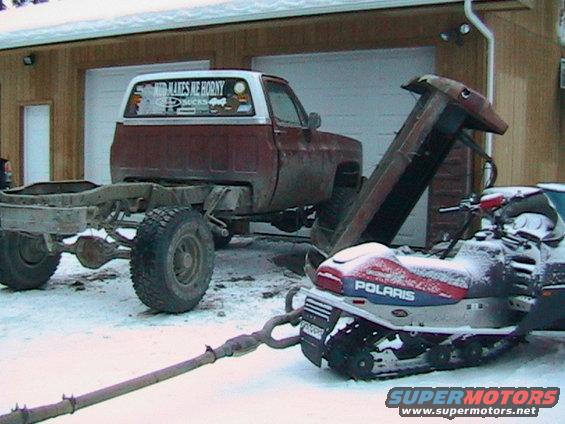 Side view of a 1981 Chevrolet C/K Pickup chassis connected to a Polaris snowmobile