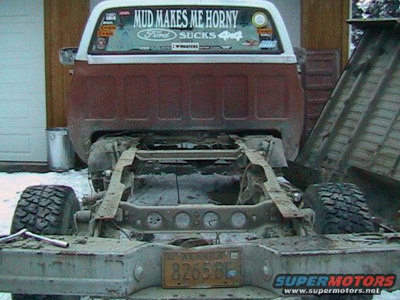 rear view of a pickup truck chassis with a dump bed attached, has a 'MUD MAKES ME HORNY' sticker on the back window