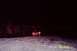 1981 Chevrolet C/K Pickup - A pickup truck is seen from the rear, driving on a snow-covered area at night with distant lights in the background.