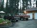 1981 Chevrolet C/K Pickup - Two Chevrolet pickup trucks are parked in front of a garage with trees behind them.