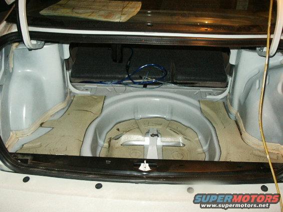 Car trunk interior with sound dampening material removed, showing white painted metal and wiring