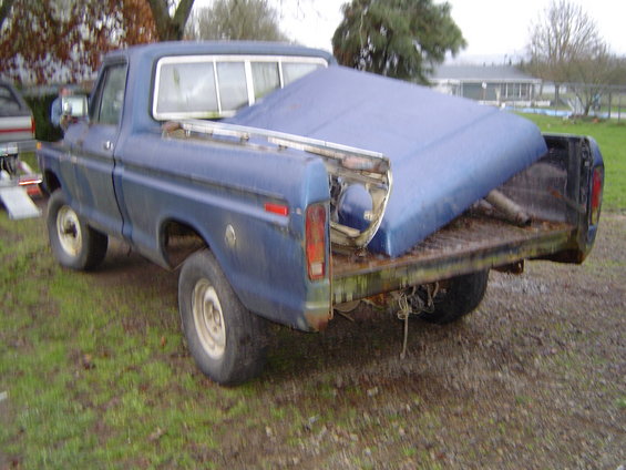 Blue pickup truck, likely a 1977 Ford, with a blue hood loaded in the bed