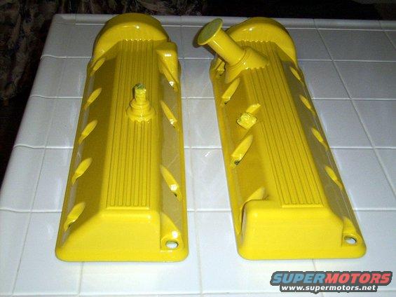 Two yellow valve covers with ribbed texture and oval cutouts, one with a cap