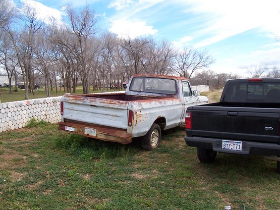 Rusty 1977 Ford F-150 pickup truck parked next to a black Ford Ranger pickup truck