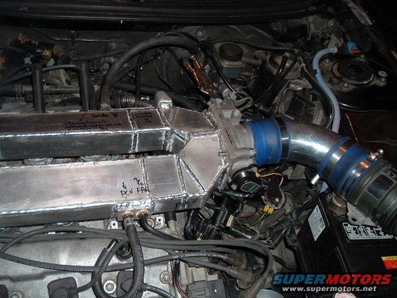Custom fabricated intake manifold with handwritten notes and PCV fittings, connected to engine components