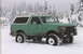 1990 Ford Bronco - A green Ford Bronco with a white top is parked in a snowy forest.