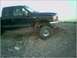 1999 Ford F-250 - A black 1999 Ford F-250 truck is shown from a three-quarter front view on a dirt and gravel lot.