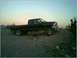 1999 Ford F-250 - A black 1999 Ford F-250 pickup truck is parked on a dirt incline at dusk, with two people observing the view.
