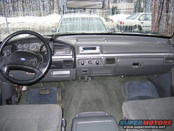 1992 Ford Bronco interior showing dashboard, steering wheel, and seats. Two other vehicles visible through the windshield