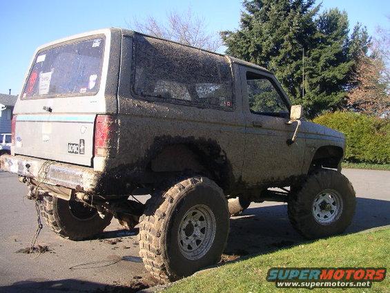Muddy 1984 Ford Bronco II lifted with big tires, parked on the side of the road
