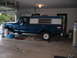 1973 Ford F-100 - A blue pickup truck with a camper shell is parked inside a garage.