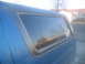 1981 Ford Bronco - Side view of a blue pickup truck's camper shell window, showing reflections.