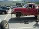 1992 Ford F-150 - A red pickup truck is parked in a lot with its front wheel removed and a jack holding it up.