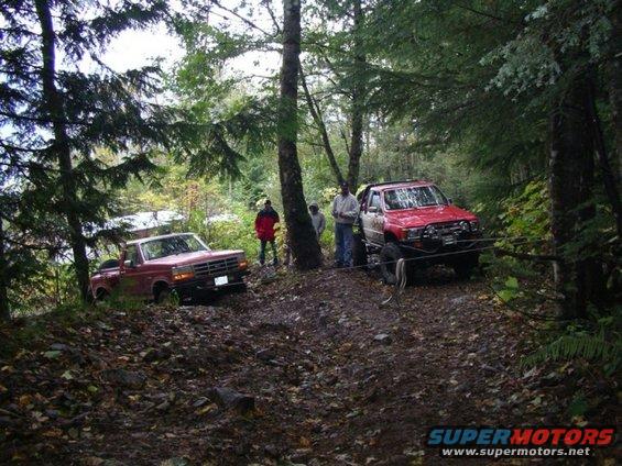 Red 1992 Ford F-150 pickup truck on a dirt path, front grille visible