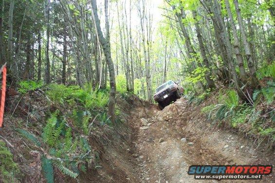 1992 Ford F-150 descending a steep, rocky dirt trail in a forest