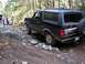 1995 Ford Bronco - A black Ford Bronco drives over rocks on a wooded trail, with other people watching.