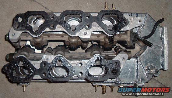 Engine intake manifold with gaskets removed, showing ports and fuel rail components