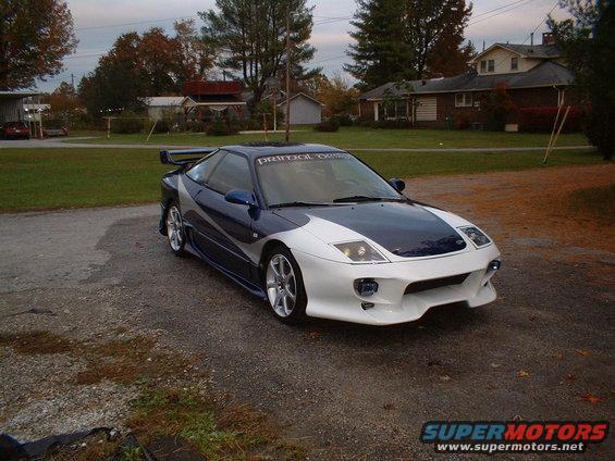 1993 Ford Probe GT with custom body kit and racing stripes, parked on gravel