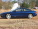 1993 Ford Probe - A blue 1993 Ford Probe GT is seen from the side, parked outdoors on a dry, grassy area.