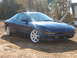 1993 Ford Probe - A blue 1993 Ford Probe GT is parked on a dirt lot with trees in the background.